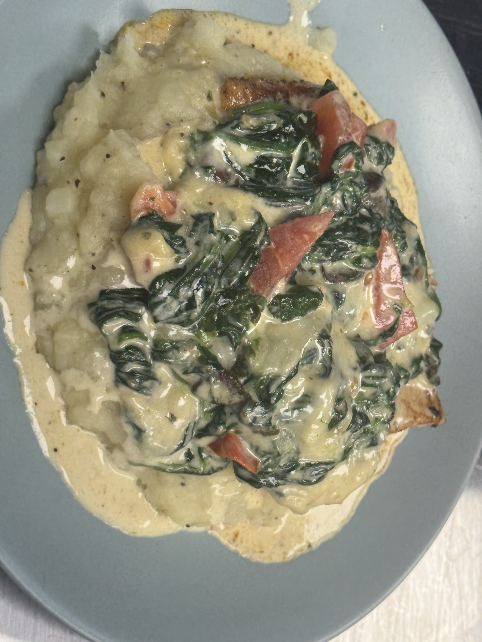 Seared salmon over garlic mashed potatoes with creamed spinach and tomato